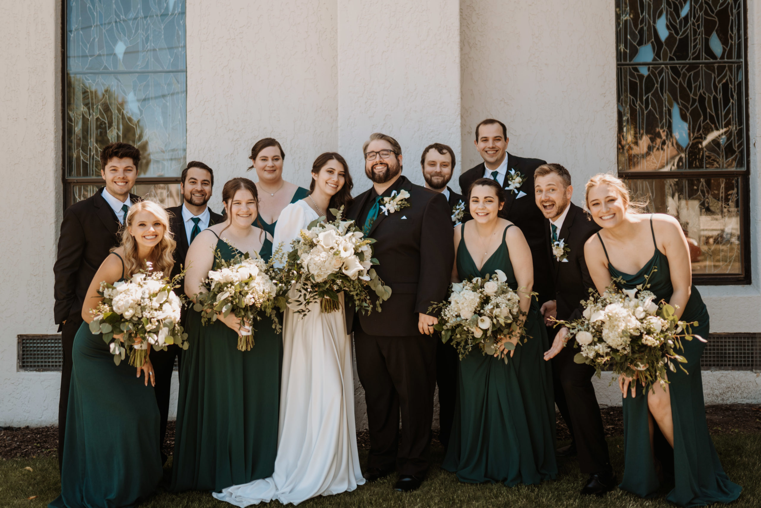 Entire wedding party in a group photo smiling and looking.